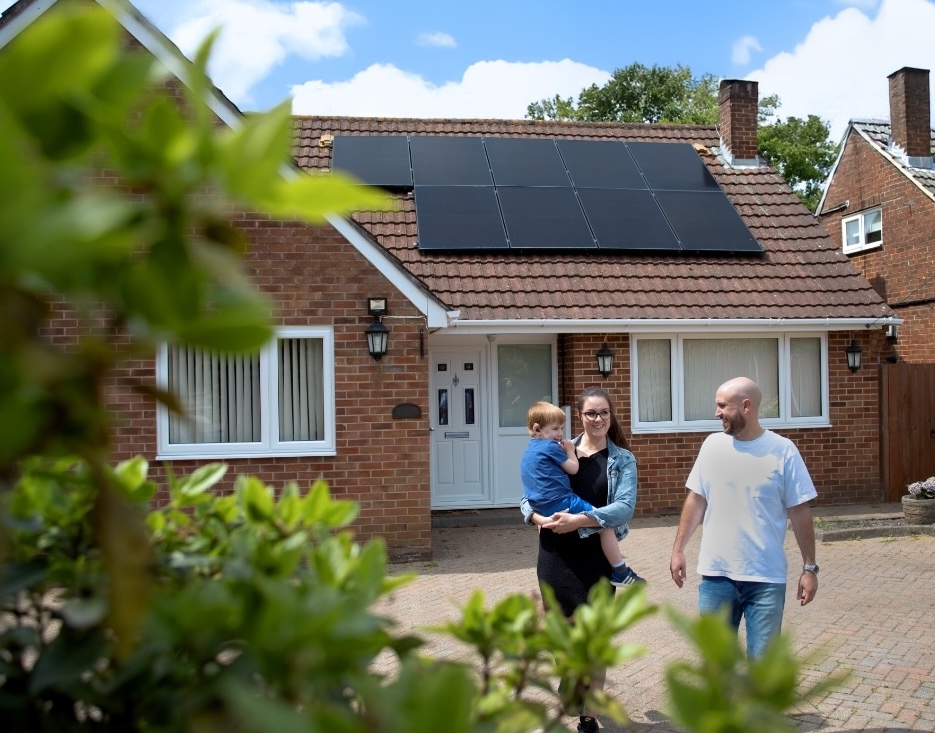 Mother, father and son walking outside their house with solar installed, representing fair access to renewable technologies.