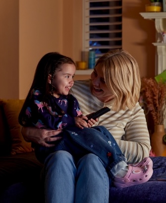 Mother and daughter sitting in a living room, smiling as they save money on their energy bills with Utilita High 5 tips.