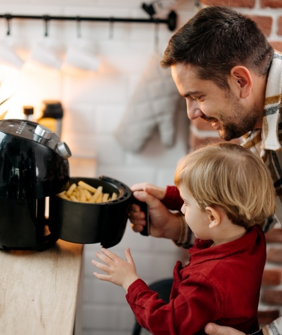 Father and son using an air fryer, highlighting energy-efficient cooking at home with Utilita Shop Smart, Cook Savvy.